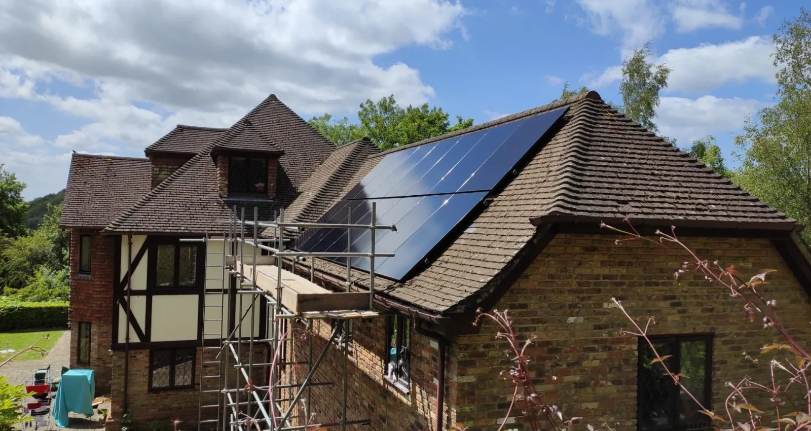 house in kent in sunshine with solar panels on roof newly installed and scaffolding