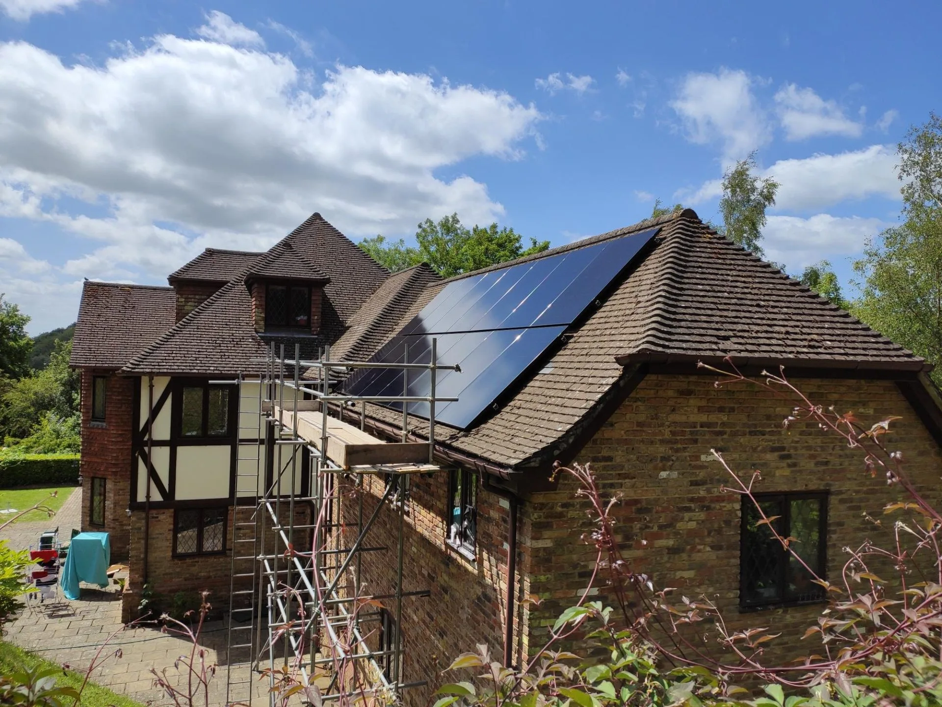 house in kent in sunshine with solar panels on roof newly installed and scaffolding