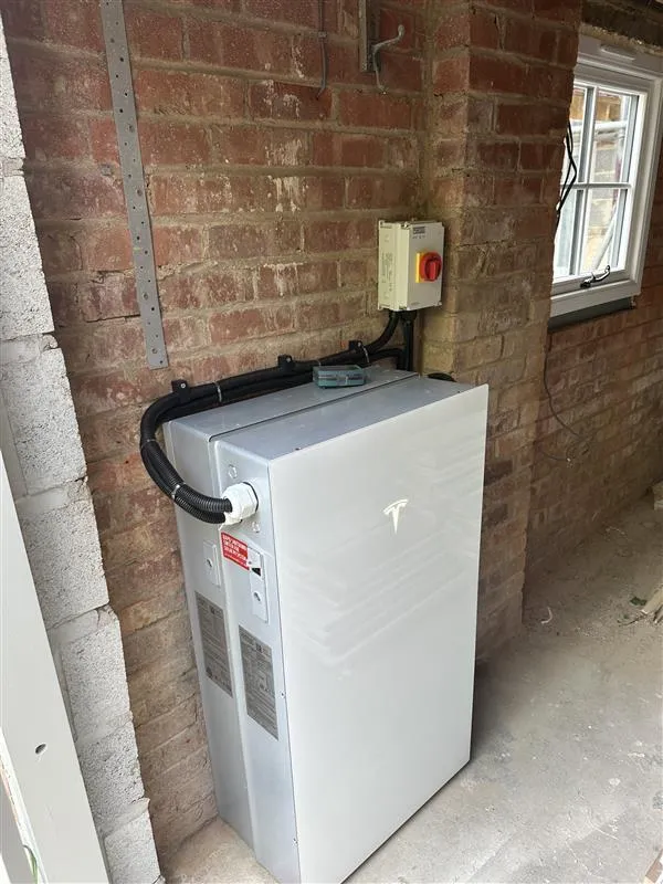 Newly installed PowerWall Battery inside a garage against a brick wall