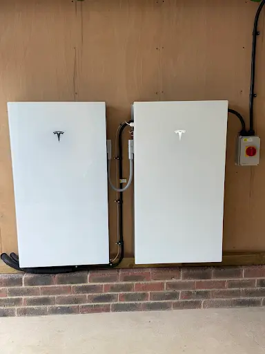 Two tesla powerwalls installed side by side on a wooden panelled wall